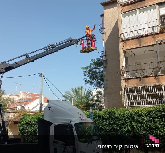 אדם במנוף עובד על איטום קיר בניין